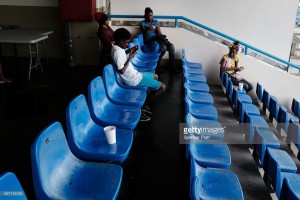 Displaced residents from the island of Barbuda sit inside a shelter at a cricket stadium on December 7, 2017 in St John's, Antigua.