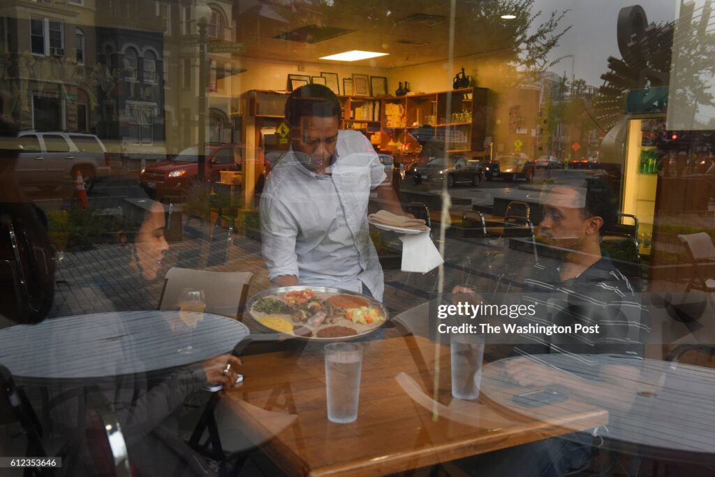Ethiopian restaurant workers serve customers in Washington, D.C., highlighting the everyday lives of Ethiopian immigrants affected by the termination of TPS.
