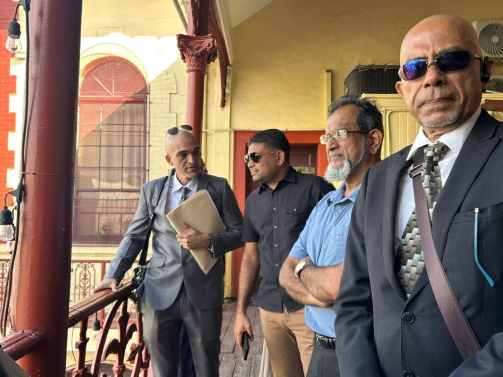 Azruddin Mohamed stands with his lawyers outside the Georgetown Magistrates’ Court during his ongoing US extradition proceedings.