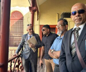 Azruddin Mohamed stands with his lawyers outside the Georgetown Magistrates’ Court during his ongoing US extradition proceedings.