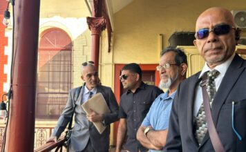 Azruddin Mohamed stands with his lawyers outside the Georgetown Magistrates’ Court during his ongoing US extradition proceedings.