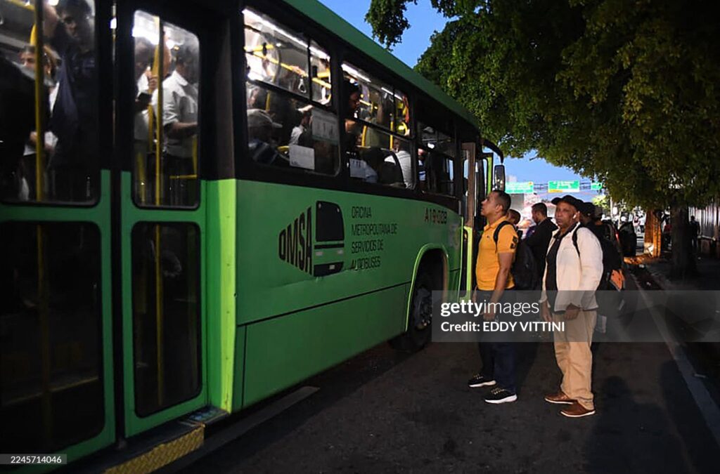 Passengers wait to board an overcrowded bus during a nationwide blackout in the Dominican Republic, causing major transportation disruptions.