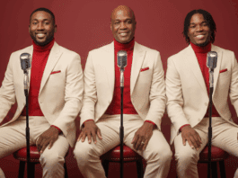 Robert Bailey seated with his sons Joel and Renaldo in coordinated cream suits and red turtlenecks, posing with vintage microphones.