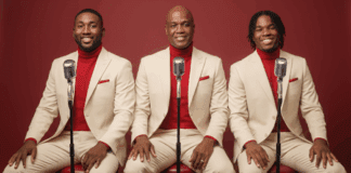 Robert Bailey seated with his sons Joel and Renaldo in coordinated cream suits and red turtlenecks, posing with vintage microphones.