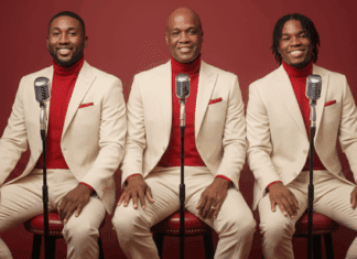 Robert Bailey seated with his sons Joel and Renaldo in coordinated cream suits and red turtlenecks, posing with vintage microphones.