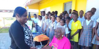 Retired Antiguan educator Teacher Gen being honored at Potters Village as students and community members look on.