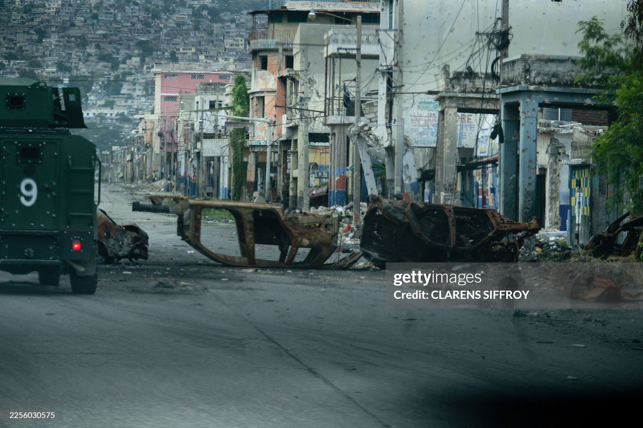 unrest-in-haiti-from-january-16-2026 A walks past cars burned by armed gangs and used as a barricade during clashes last week with Haitian security forces on a deserted street in the city center, seen from an armored police vehicle during a patrol, in Port-au-Prince on January 16, 2026. An
