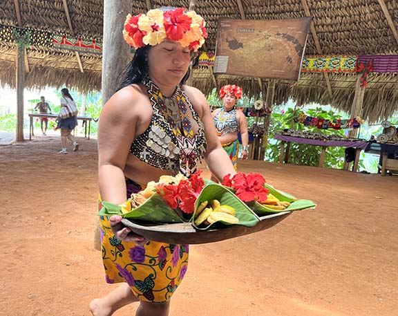 An Embera woman serves tourists tostones and fried tilapia in banana leave pouches in Panama. (NewsAmericasnow.com image)